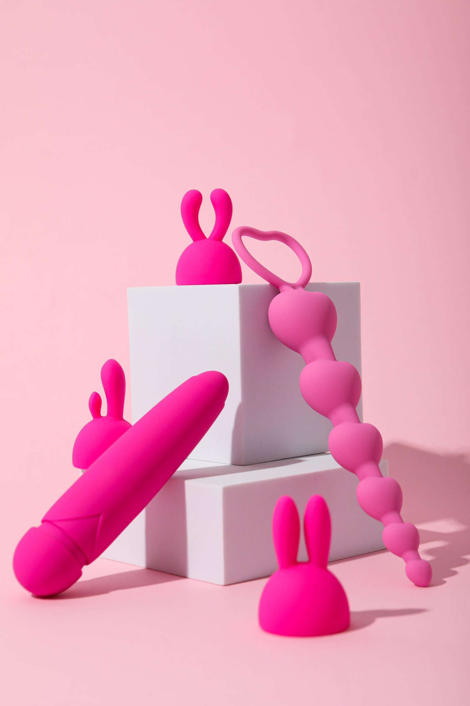 Composition of pink sex toys with cubes on a pink background