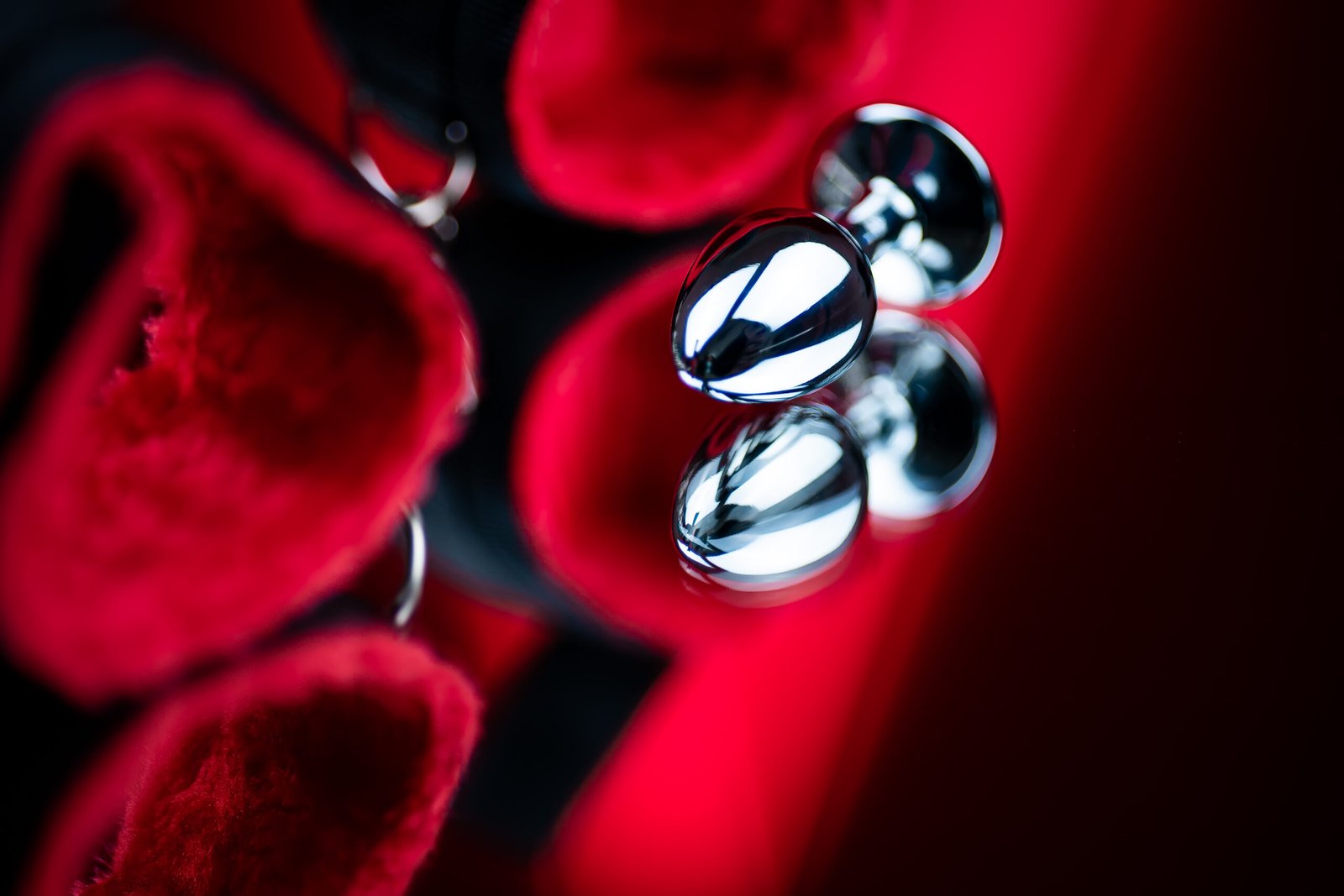 erotic bdsm toys for intimate sex games metal butt plug on the background of red handcuffs