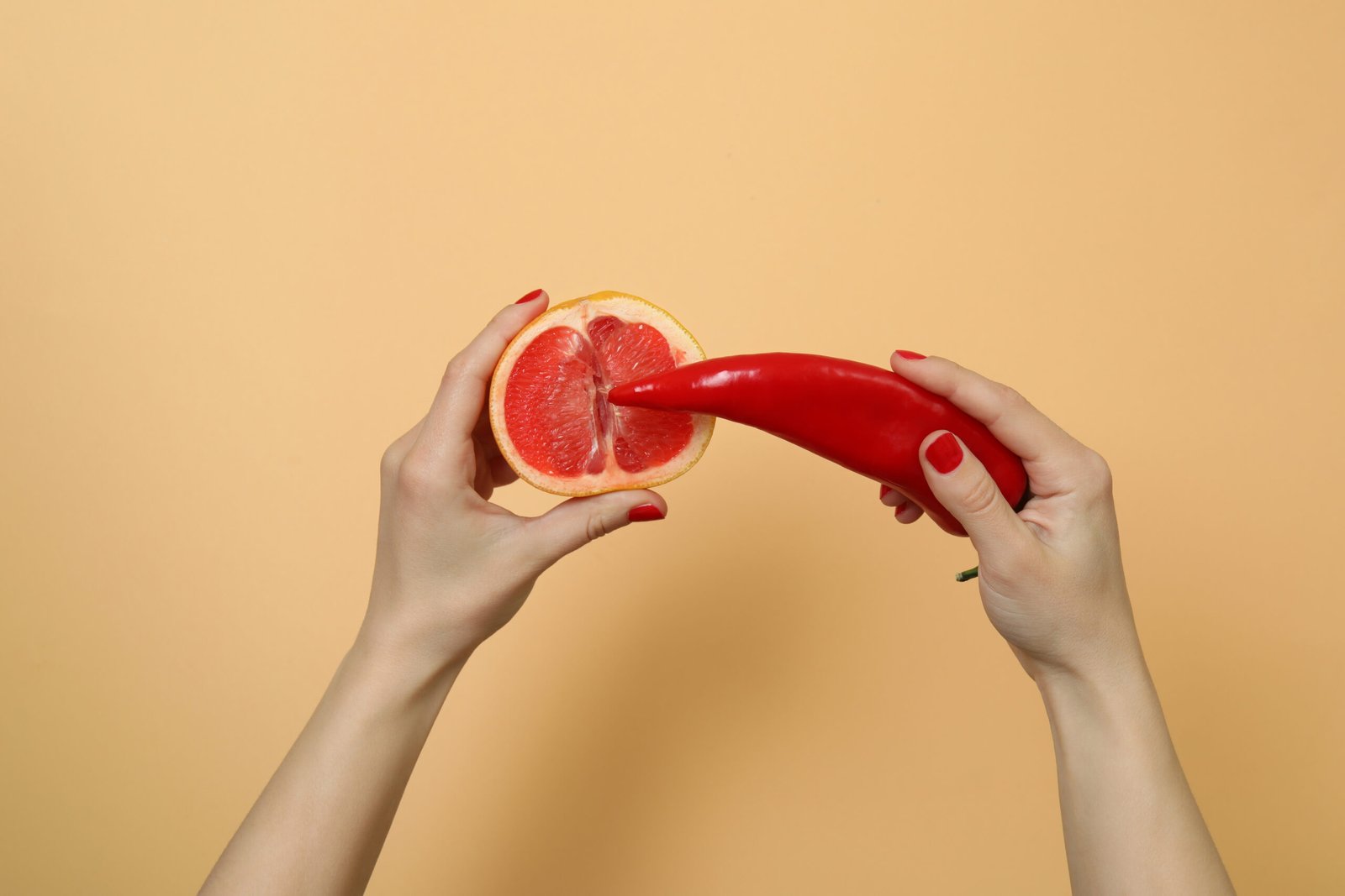 Female hands hold pepper and grapefruit on beige background