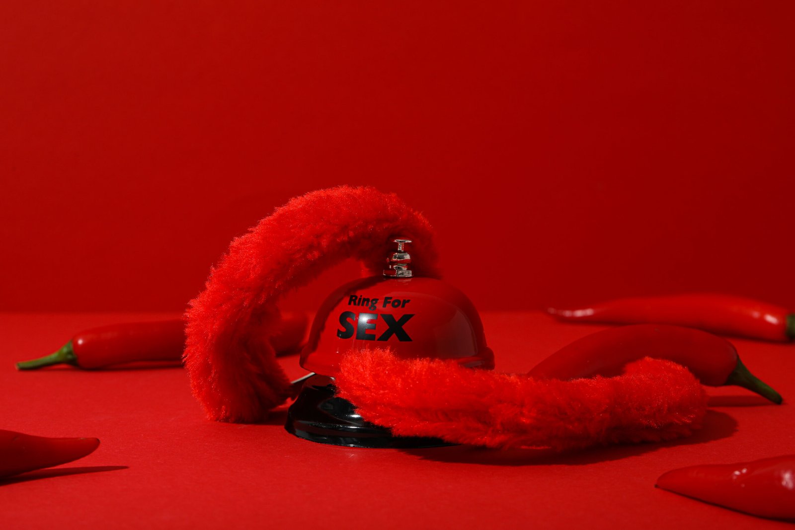 Handcuffs and a bell for sex with pepper, on a red background