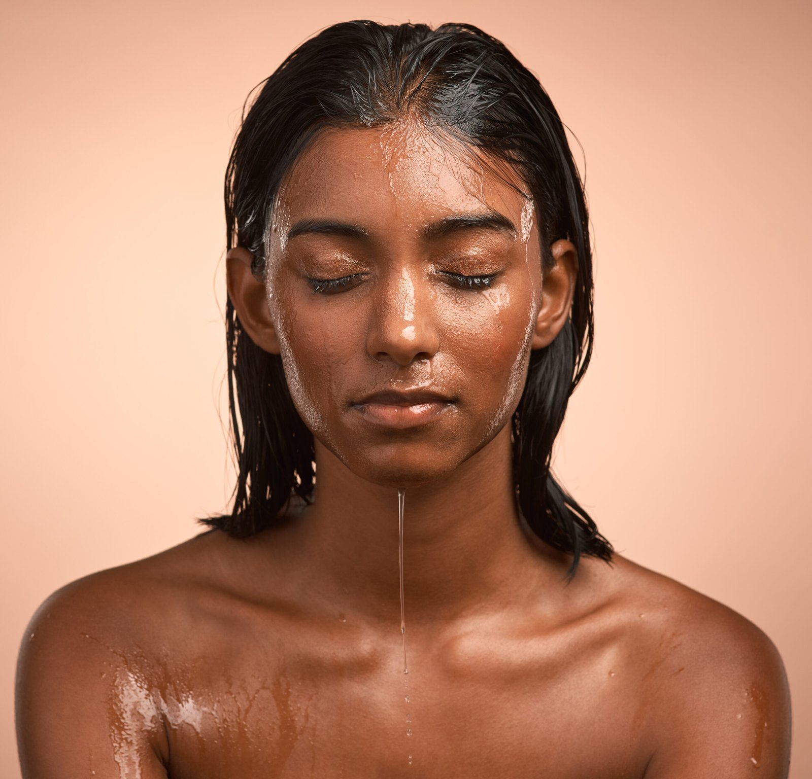 Shot of a young attractive woman doing her daily skincare routine against a brown background.