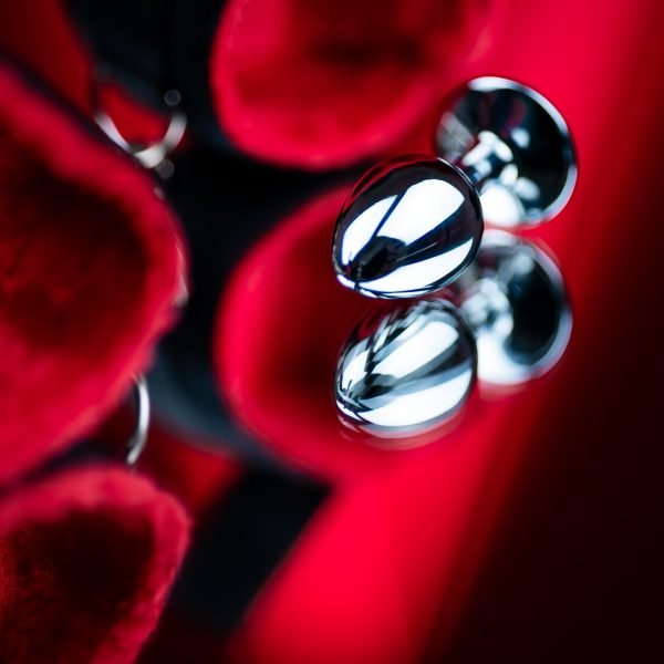 erotic bdsm toys for intimate sex games metal butt plug on the background of red handcuffs